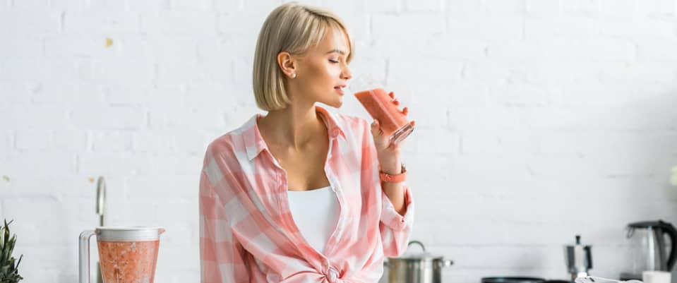 blonde adult woman drinking a healthy fruit juice