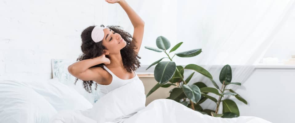 adult woman stretching on her bed upon waking up